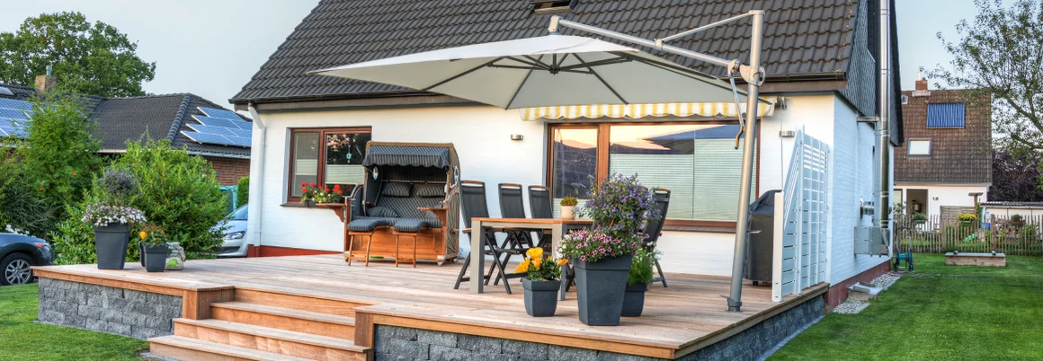 Holzterrasse mit Gartenmöbeln und Sonnenschirm